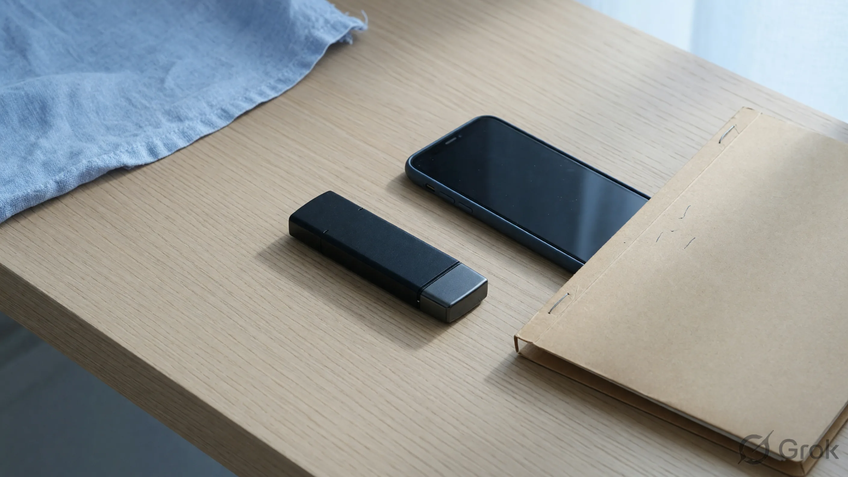 Unlabeled black flash drive beside a facedown phone