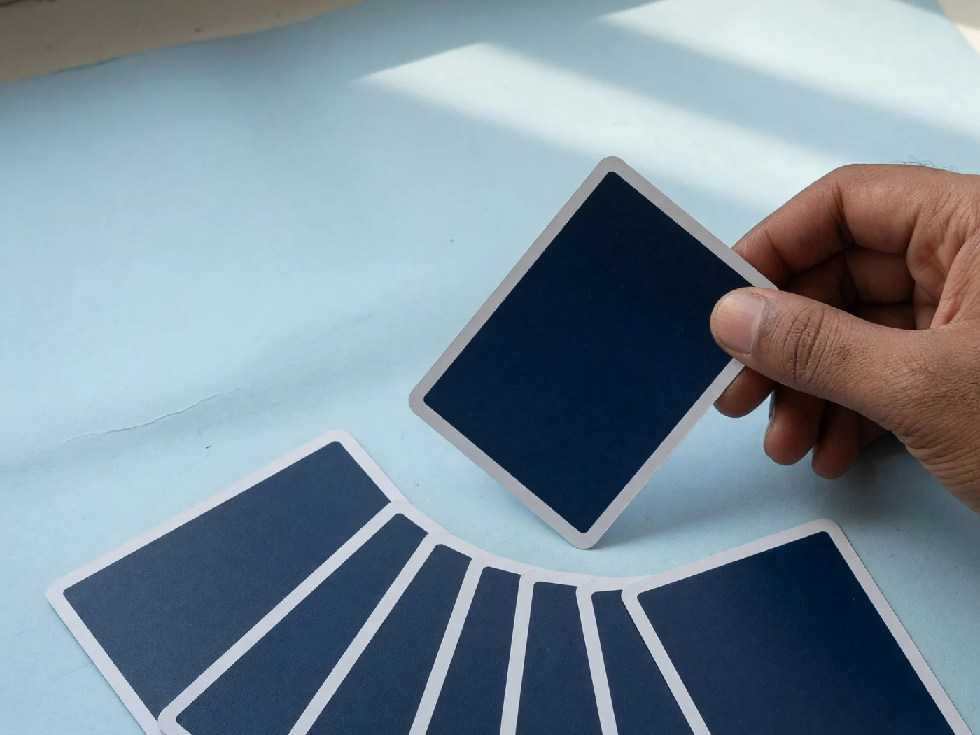 Fingers lifting one card a few millimetres inside a private fan