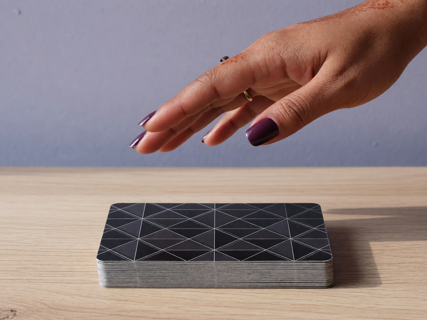 Fingers hovering above a closed facedown deck without touching