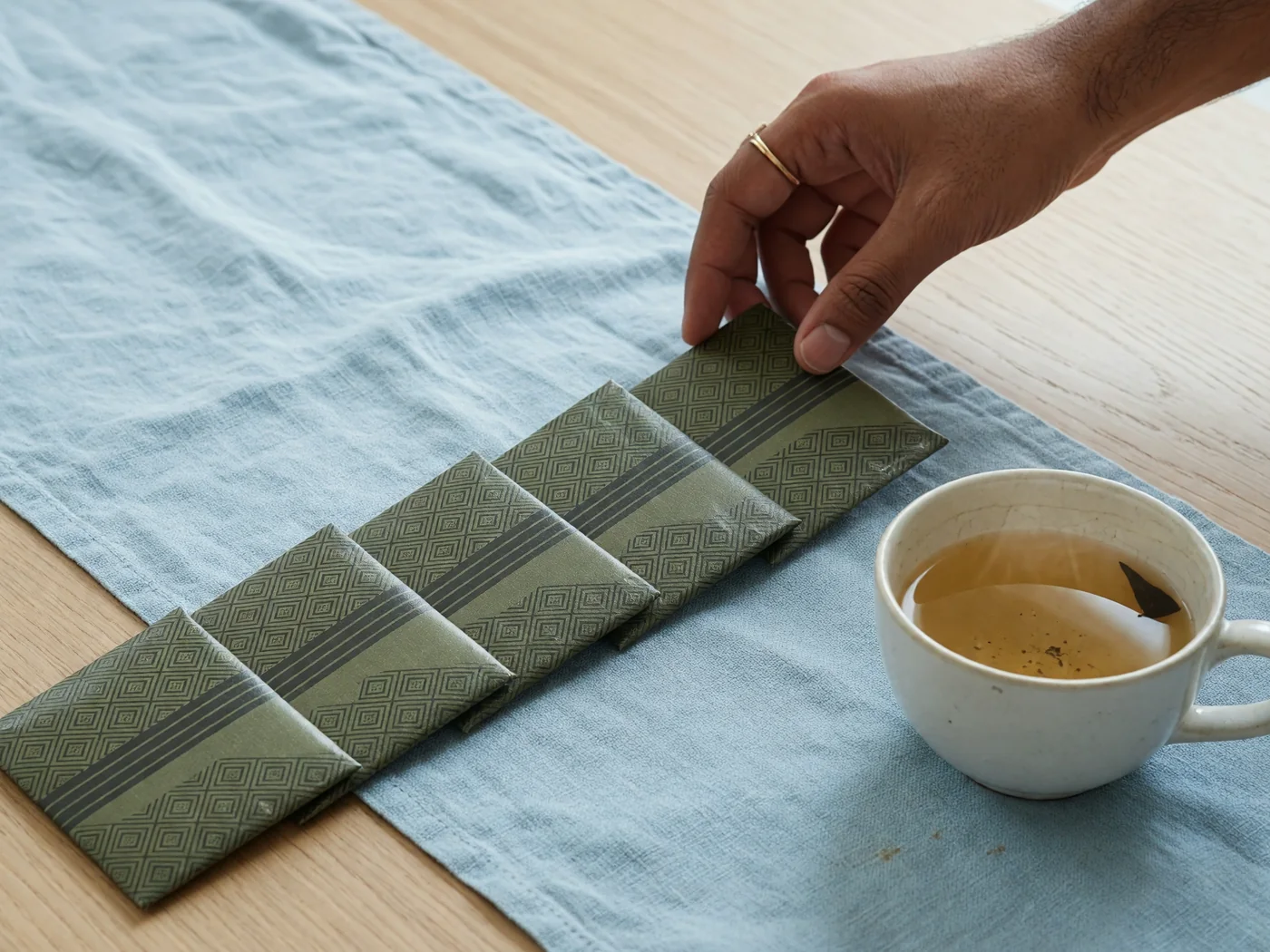 Dealer hand placing equal facedown packets along a pale oak table