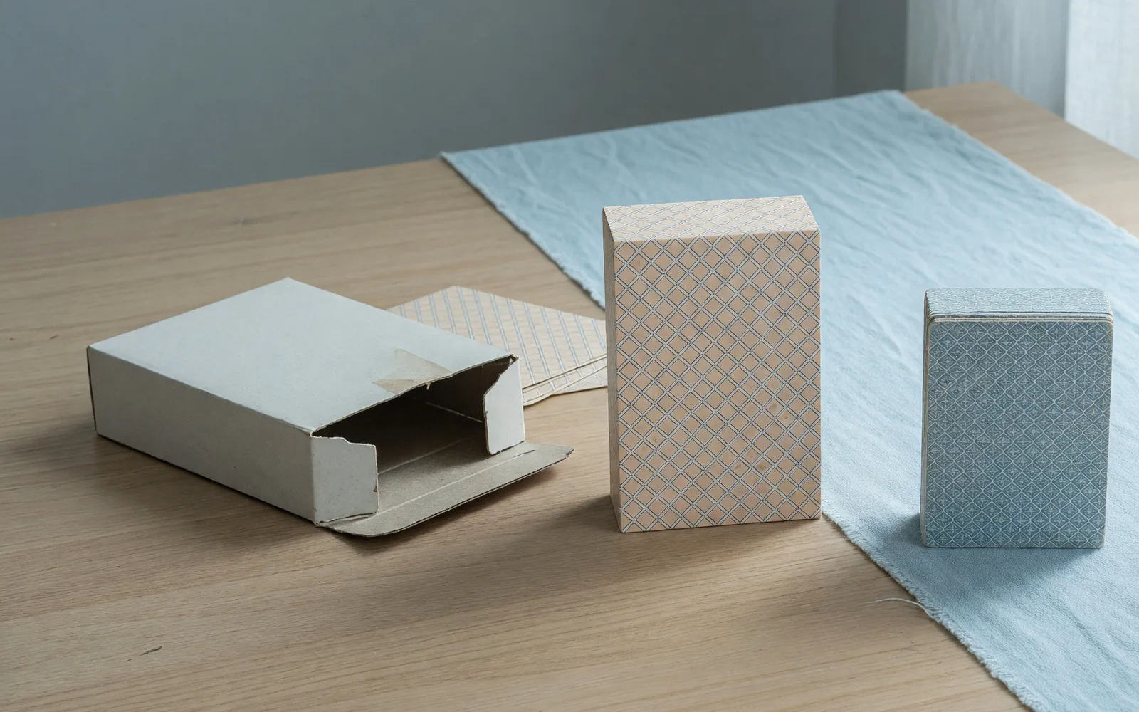 Open card box and two facedown packets of different heights on pale oak