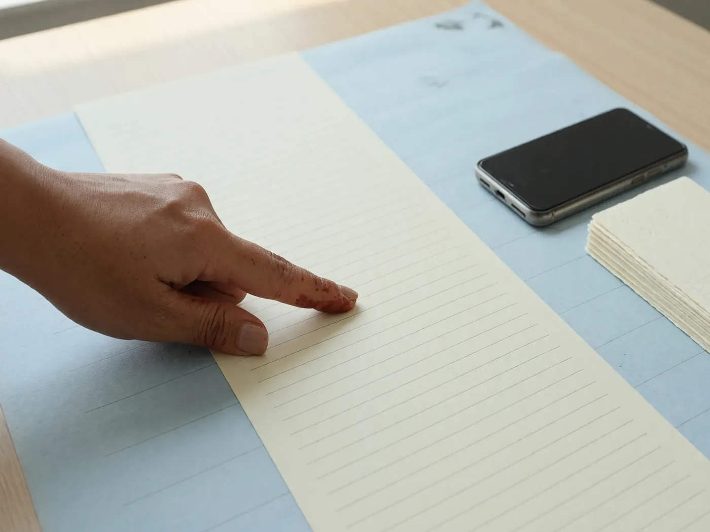 Index finger scanning a long paper list with soft ruling and no readable type