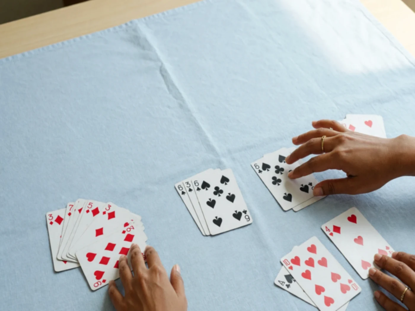 Finished card groups on linen with hands withdrawing